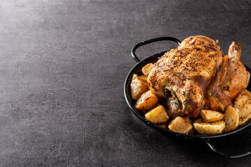 Homemade roasted chicken with potatoes on black background. Copy space