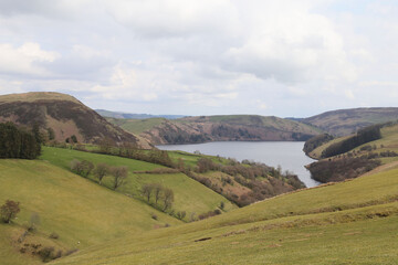 Fototapeta na wymiar A view across rolling hills and farmland to Llyn Clywedog, Powys, Wales.