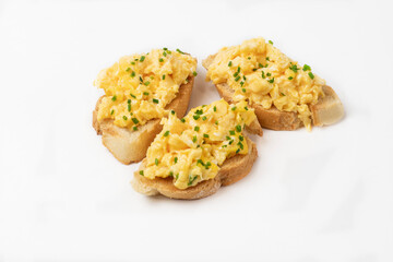 Scrambled eggs served on bread toast on white background