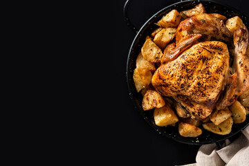Homemade roasted chicken with potatoes on black background. Copy space