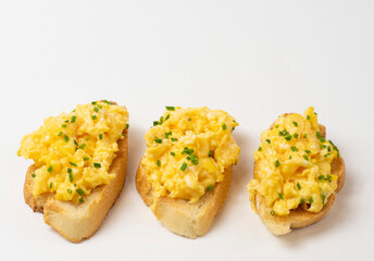 Scrambled eggs served on bread toast on white background