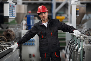 Fototapeta premium Portrait of worker in factory. Young man with helmet working in factory..
