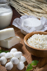 Different homemade cottage cheese with milk on wooden table..