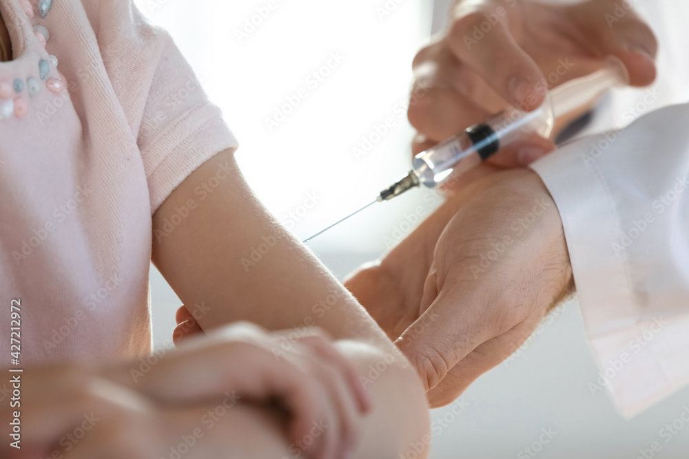 Wall mural Crop close up of male doctor or GP hold syringe make injection give vaccine to small girl patient in clinic. Man pediatrician or nurse vaccinate little kid child in hospital. Vaccination concept.