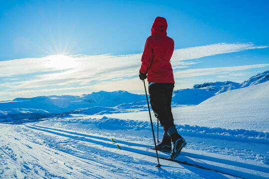 Young woman cross country skiing on a sunny day in snow covered mountains.