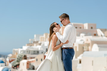 Fototapeta na wymiar The couple is sitting on the roof in Santorini, hugging and laughing