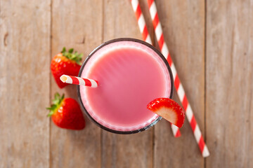 Strawberry milkshake in glass on rustic wooden table.Top view