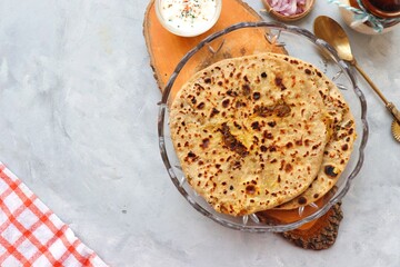 Indian traditional Hot Onion Paratha with yogurt. Indian onion stuffed Flatbread. also known as Pyaz ke parathe in Hindi. over a light background with copy space.