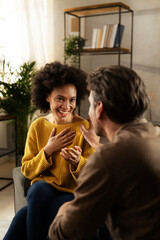 Young couple sitting and talking at home. Woman and man flirting and laughing...
