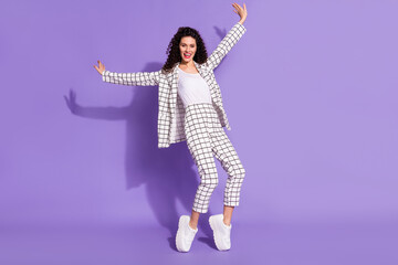 Full length photo portrait of excited girl standing on tip toes isolated on vivid purple colored background