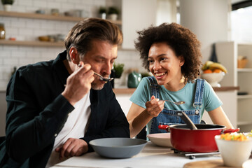 Boyfriend and girlfriend eating lunch with friends at home. Young couple enjoying the company of their friends..