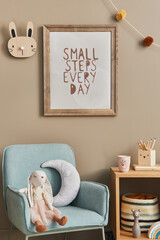 Cozy interior of child room with mint armchair, brown mock up poster frame, toys, teddy bear, dolls, plush animal, decoration. Beige  wall. Warm kid space. Template.