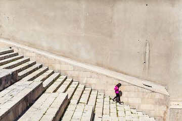 Young girl walking down the stairs Stone steps at the city Baku Azerbaijan. Concrete staircase with concrete wall side view. Texture background and wallpaper. Scenic photo with copy space
