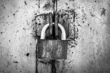 rusty lock on a texture of old, metal, iron, black and white door, which the old paint flaking. the passage is closed. locked. place for text.