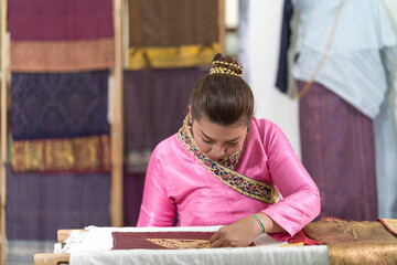 Crafts and craftsmanship.  Yong woman are Sewing silk. Asian woman embroidering golden thread on silk.