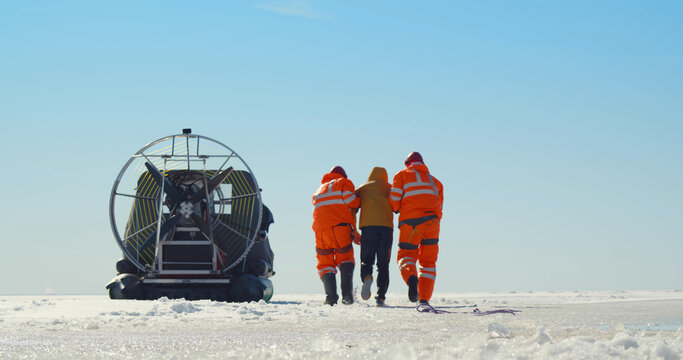 Lifesavers With Rope Pulling Drowning Man Out Of Icy Water In Winter