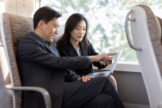 Successful business people using laptop on high-speed train