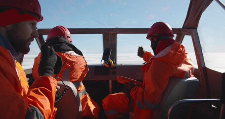 Lifeguards in hovercraft talking on walkie-talkie and using digital tablet navigating in arctic - obrazy, fototapety, plakaty