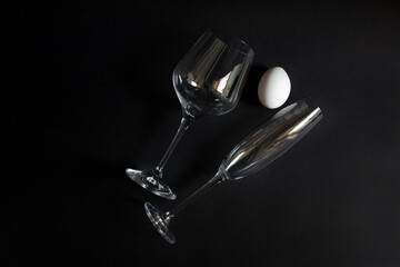 white chicken eggs on a black background with glasses. glasses on black background