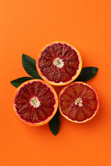 Red orange halves and leaves on orange background