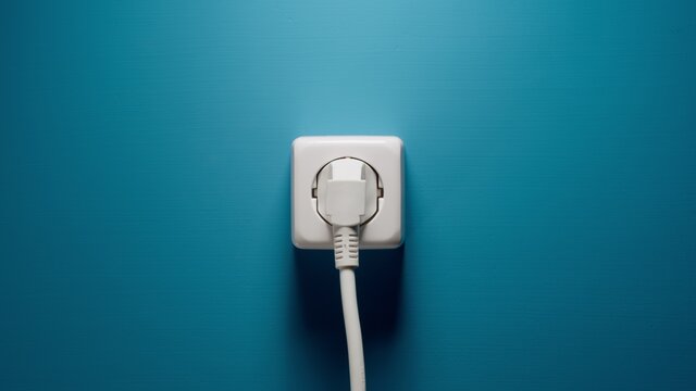 Plugged into an electrical outlet on a blue wall
