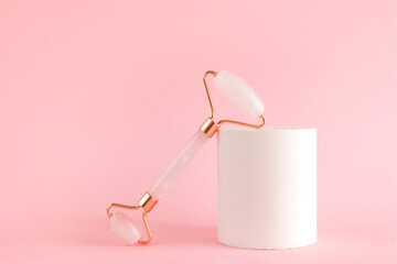 Rose quartz roller for facial massage on a concrete podium. Beauty and home skin care concept....