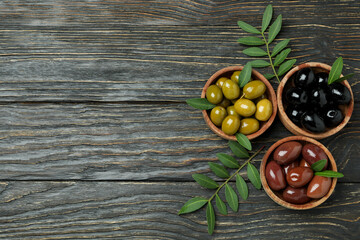 Bowls of different olives on wooden background