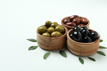 Wooden bowls of olives and leaves on white background