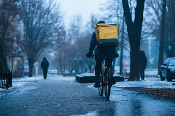 Courier delivering food with backpack on winter icy road