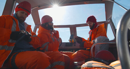 Lifeguards putting on uniform sitting in boat in winter