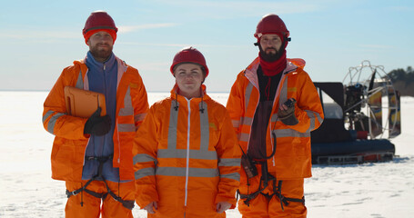 Portrait of professional rescue service team in uniform posing at camera on frozen bay