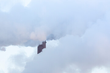 A industrial chimney in the clouds of steam. Sunny winter day.