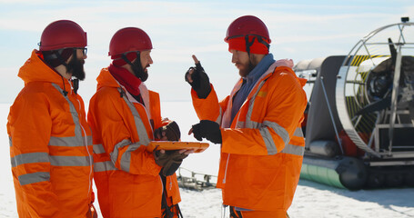 Lifesaving team discussing patrol route on digital tablet standing in arctic