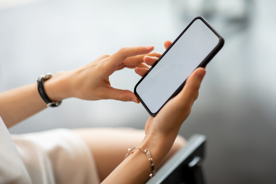 Mockup image of a woman using smartphone with blank screen on wooden table