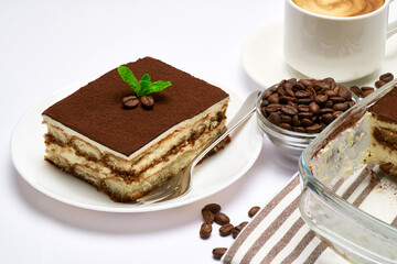 Traditional Italian Tiramisu dessert in glass baking dish, portion on plate and cup of coffee isolated on white background