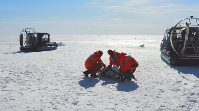 Rescuers transporting victim on stretchers on ice in arctic