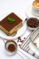 Traditional Italian Tiramisu dessert in glass baking dish, portion on plate and cup of coffee isolated on white background