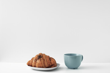 Blue mug and croissants on a white background. Eco-friendly and natural materials in the decor, dessert. Copy space, mock up.
