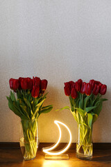 Neon moon sign with beautiful red tulips. Trendy style. Floral background. Neon sign. Custom neon. Home decor.