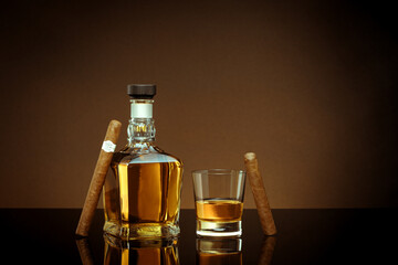 close up view of cigar, bottle of cognac and a glass aside on brown back. 