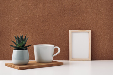 Frame, vase with eucalyptus and cup, cork background. Mock up, copy space. Folk.