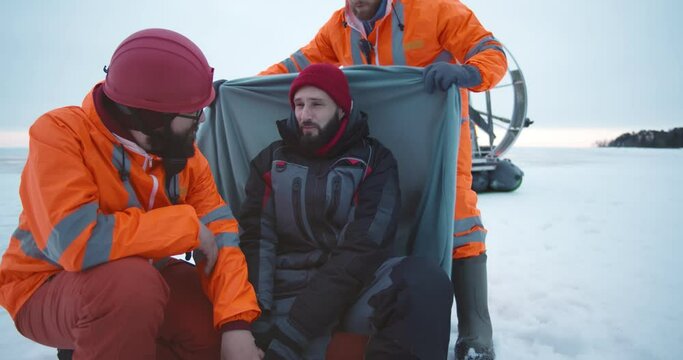 Coast guards rescuing young man with injured leg on frozen lake