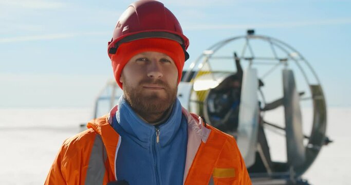 Close up portrait of handsome bearded lifeguard putting on hardhat posing at camera