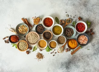 Zelfklevend Fotobehang Various dry spices in small bowls and raw herbs flat lay on grey background. © senteliaolga