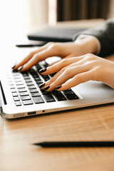 Woman working at home office, hand on the keyboard close up. Woman working at home with laptop writes a blog. Female hands on the keyboard