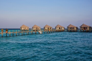 Golden Hour View of Water Villas in Maldives. Overwater Bungalow, Wooden Pier and Laccadive Sea in Maldivian Resort.