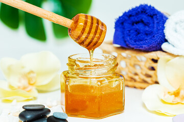 Gold honey in a jar, orchid flowers, towels and scented candles.