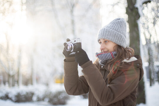 Woman photographer with retro camera in snowy weather at winter