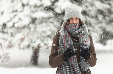 Fototapeta premium Portrait of attractive woman in warm clothes in winter snowy weather outdoors
