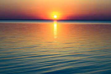 Fototapeta premium Bright beautiful sunset at the calm sea. Solar disk over water.